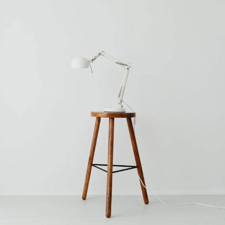 Three-legged wooden stool with a small lamp